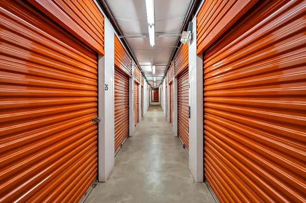 Indoor climate controlled storage hallway with orange roll-up unit doors